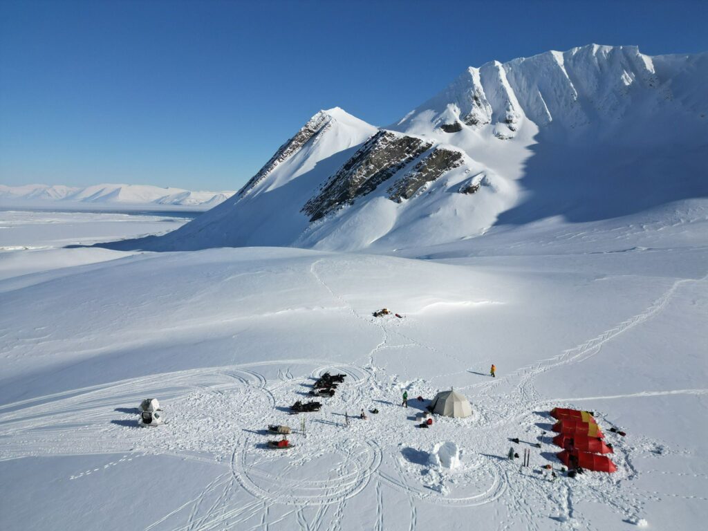 Experienced skiers descending untouched Artic slope down to basecamp on the ski camp expedition