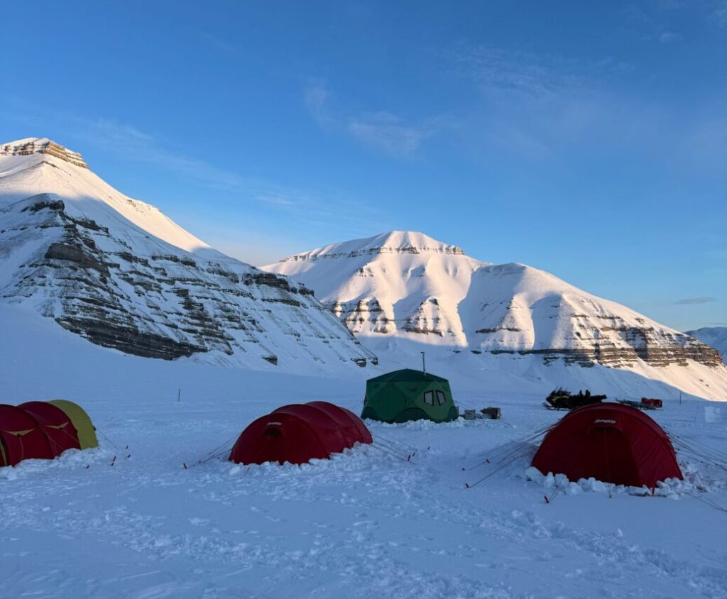 Basecamp on Svalbard with tents surrounded by snowcovered mountains.