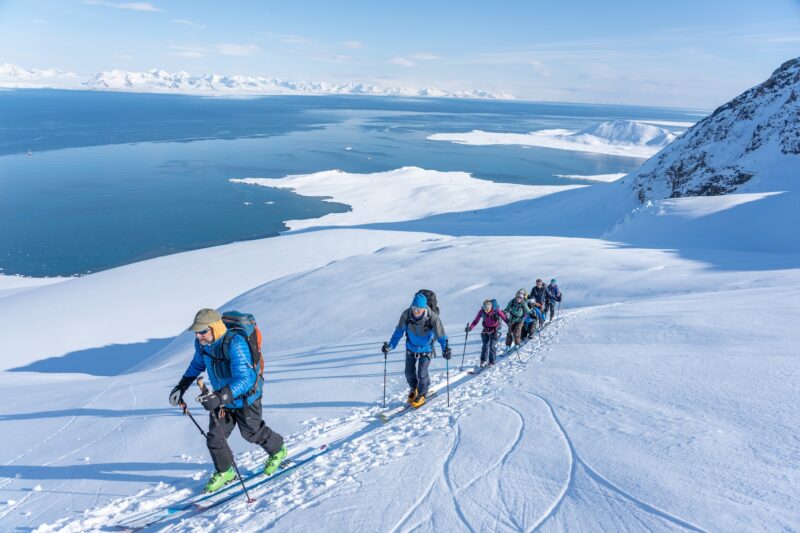 Backcountry skiiers on a remote mountain in Svalbard for the Ski and sail expedition with Backyard Svalbard.