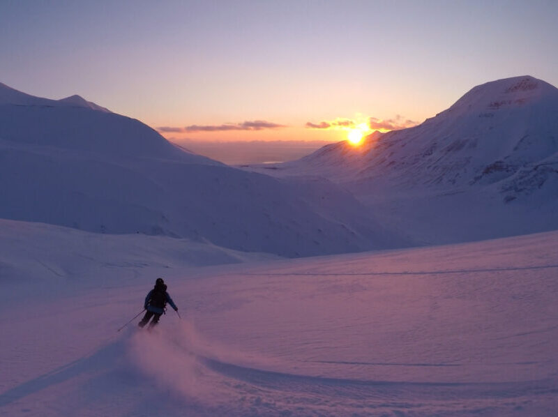 Guided ski touring on Svalbard enjoying a descent with view to the midnight sun