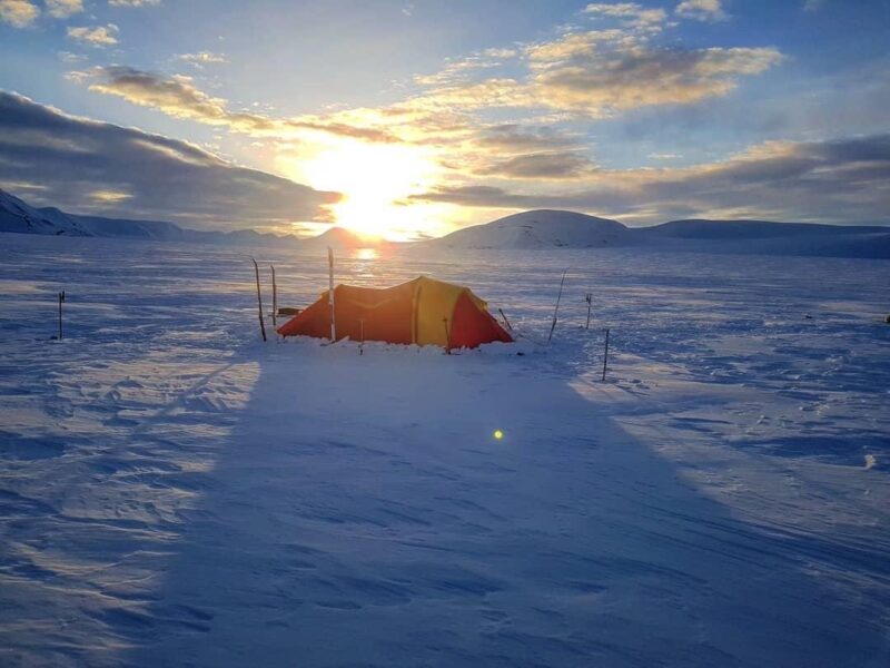 The red tent pitched in the snowcovered wilderness in Svalbard on the ski crossing expedition