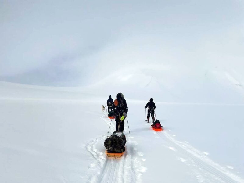 Skiers pulling a pulk (sleds) cross country in Svalbards wilderness during this 4 day ski expedition in the Arctic