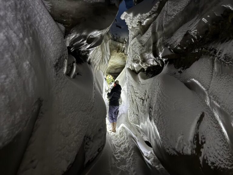 A small group of explorers hiking through the silent glacier landscape to the natural ice cave in Svalbard