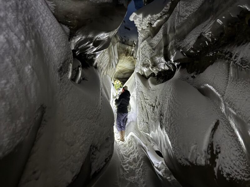 A small group of explorers hiking through the silent glacier landscape to the natural ice cave in Svalbard