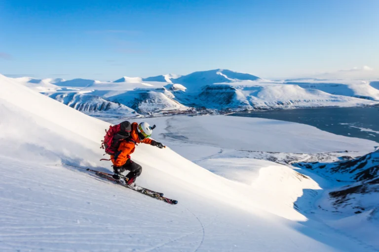 Svalbard Ski touring with backcountry skier on mountain with Longyearbyen in the background