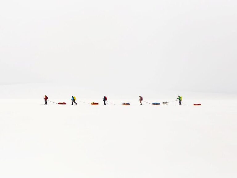 Skiiers walking in line and pulling a pulk on the ski crossing expedition in Svalbard.