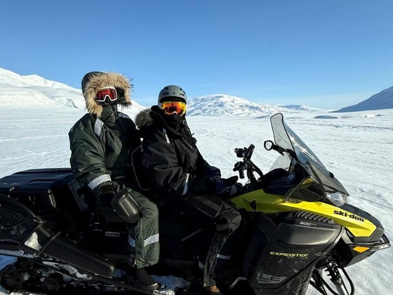 Driving the snowmobile through snowcovered Svalbard landscape to a magical ice cave in the wilderness