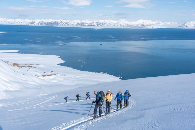 Backcountry skiiers walking up the snowcovered mountain from sea to summit on Svalbard.