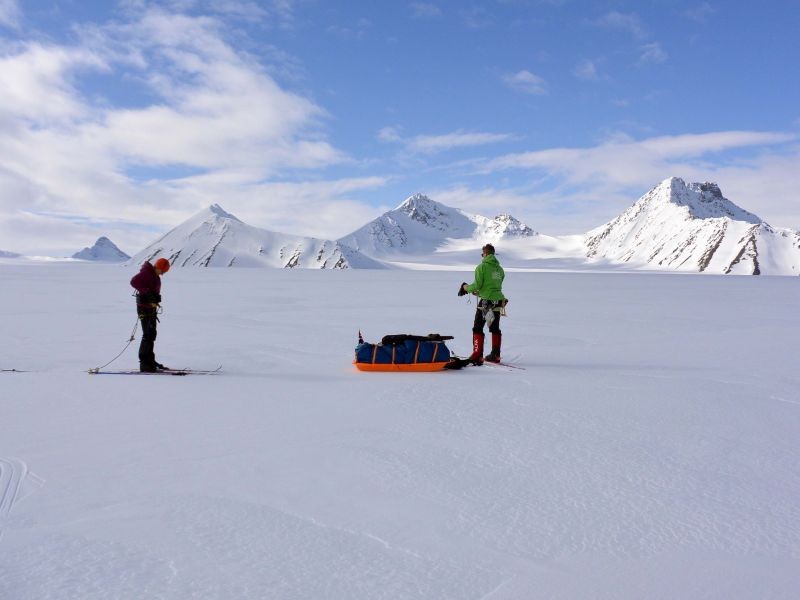 Two skiiers talking a break in the wilderness on a Svalbard ski crossing expedition with pulk