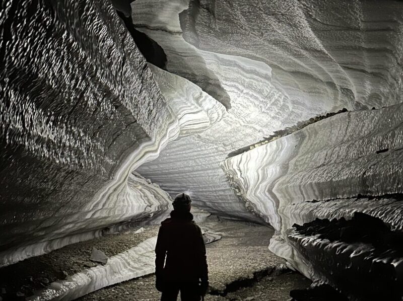 Guided tour in ice cave with helmets and headlamps exploring the ice crystals inside a Svalbard ice cave